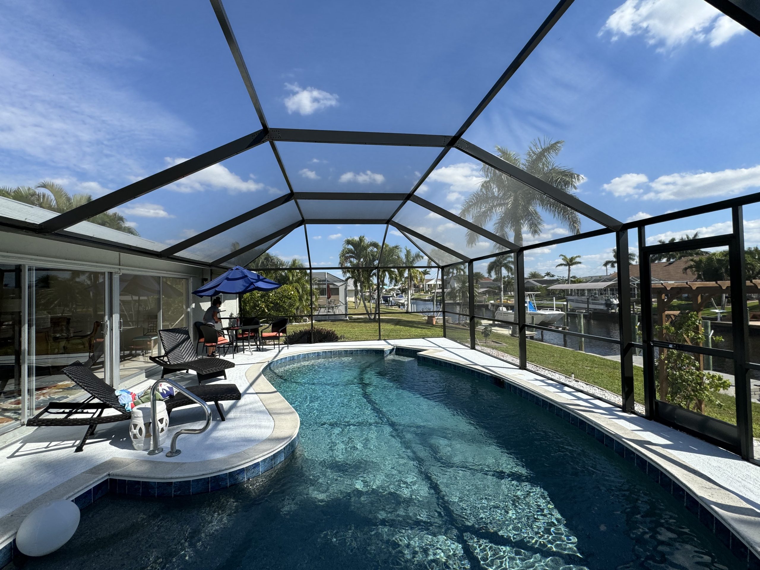 Screened pool enclosure with panoramic backyard and canal views