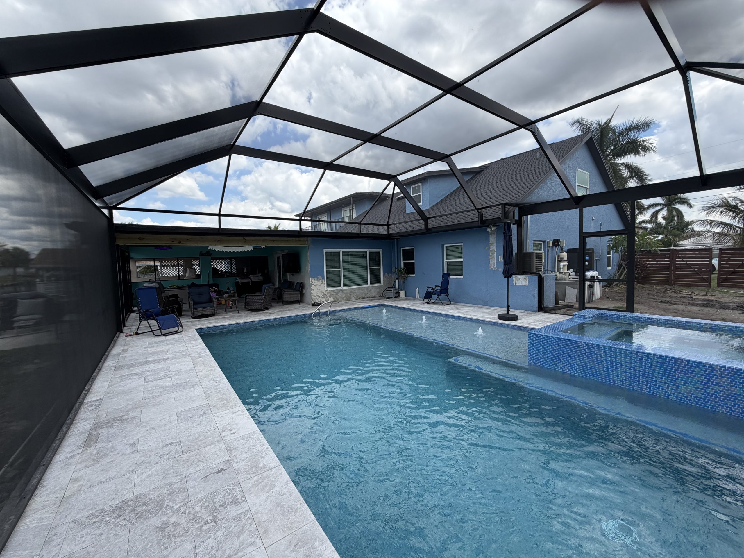 Custom pool screen enclosure with swimming pool, paved deck and overhead shade panels
